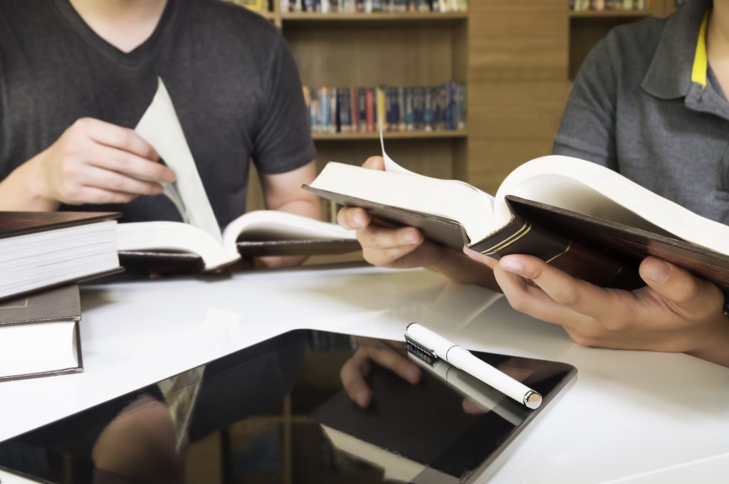 Young man and woman reading book in library.People studying together in a library