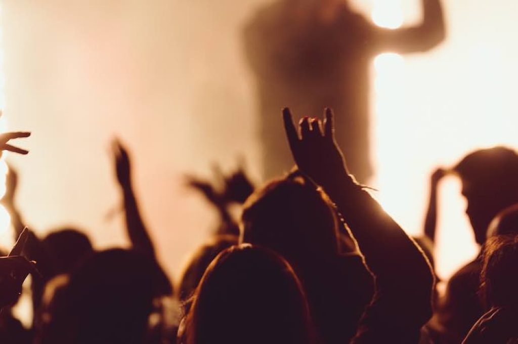 People dancing at a concert while the singer is performing surrounded with lights