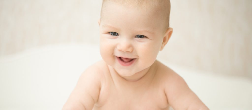 Portrait of a beautiful expressive happy laughing baby, holds head up. Family, baby development concept photo, lifestyle